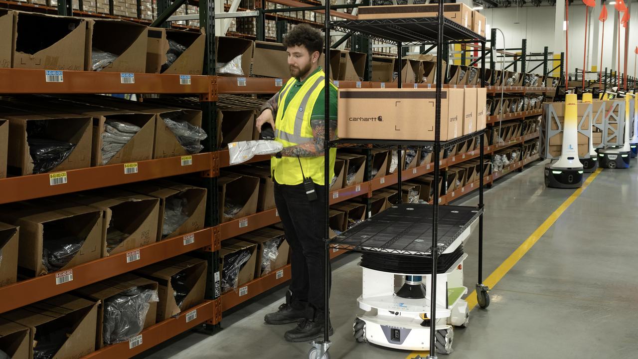 Warehouse robot assisting worker with order picking.